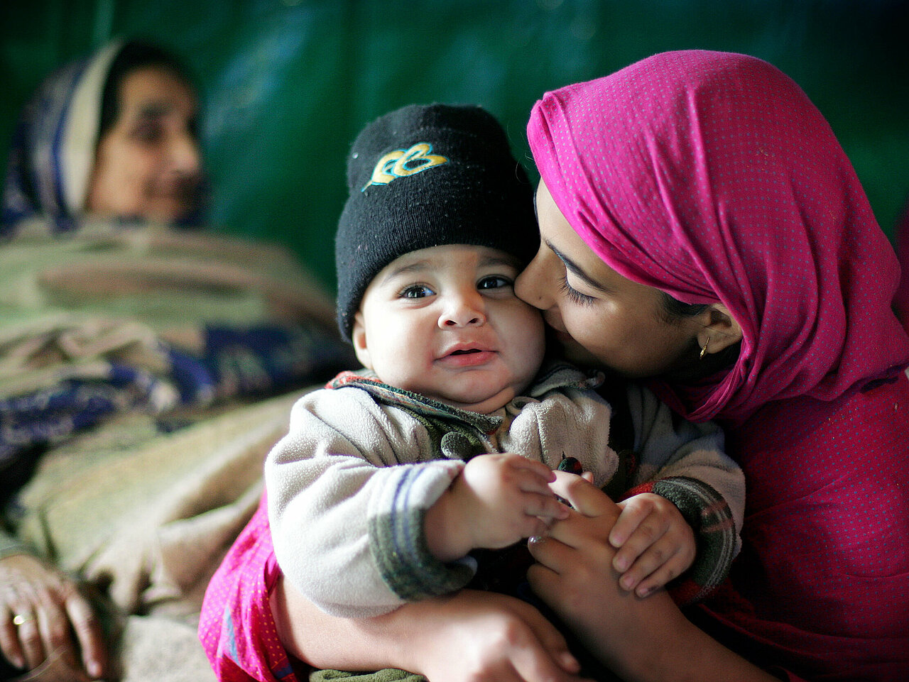 Pakistanisches Mädchen hält Baby im Arm