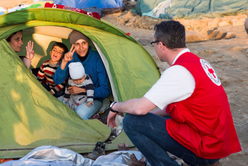 Rotkreuzhelfer mit Familie vor Zelt
