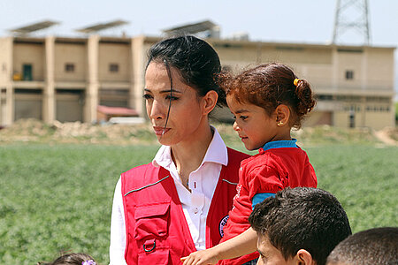 Foto: DRK-Botschafterin Zohre Esmaeli mit einem libanesischem Mädchen auf dem Arm