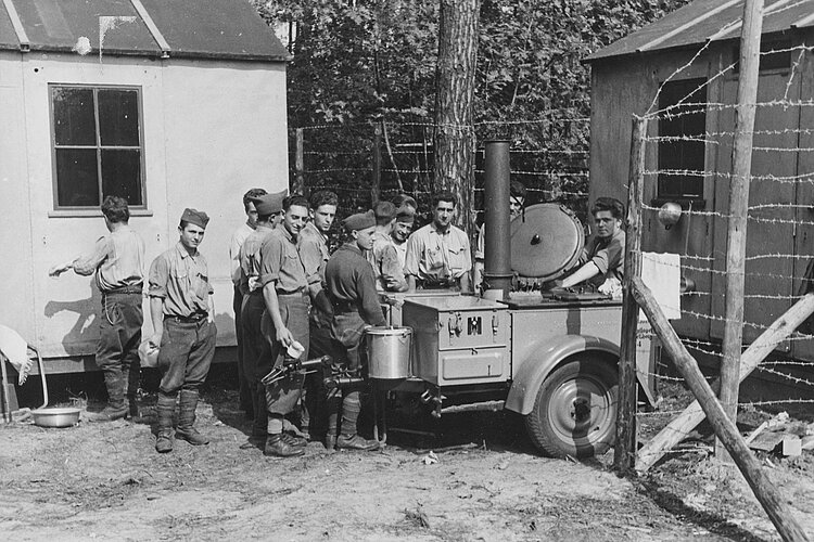 Männer stehen an einer Feldküche