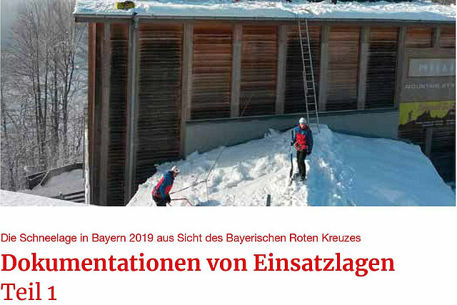 Einsatzkräfte der Bergwacht schaufeln Schnee vom Dach eines Hauses