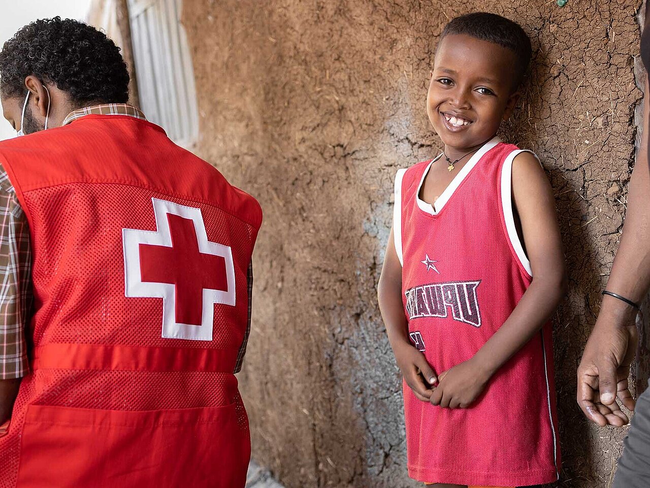 Lachender Junge in Äthiopien mit Rotkreuz-Helfer