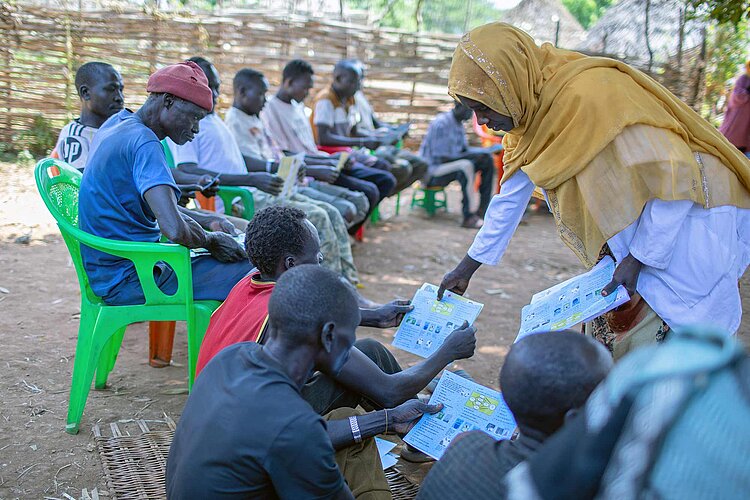 Helferin teilt Flyer aus