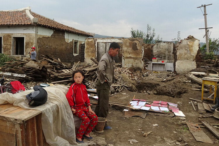 Katastrophe durch Überschwemmung: Opfer des Taifuns vor den Trümmern ihres Hauses.
