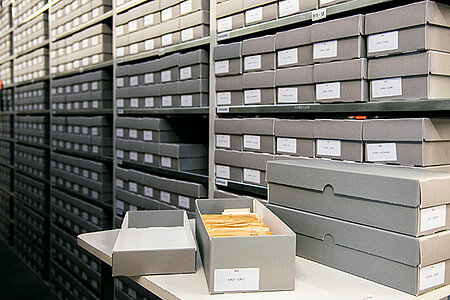 Karton mit Karten vor einem Archiv-Regal