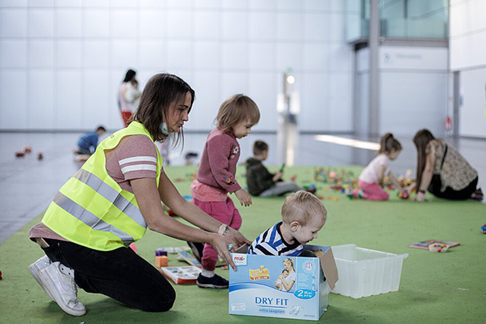 DRKlerin spielt mit Kindern in Kinderecke