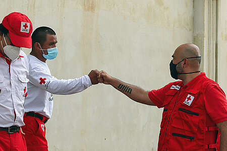 Rotkreuzmitarbeiter in Lateinamerika grüßen sich mit Faustgruß