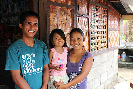 Philippinische Familie vor ihrem neuen Bambushaus nach dem Wirbelsturm