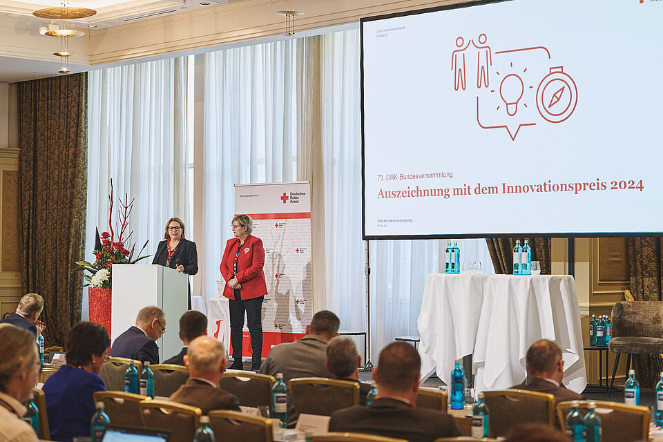 Verleihung des DRK-Innovationspreises auf der 73. Bundesversammlung des DRK. Auf dem Podium Gisela Wedler (Teamleiterin Digitalisierung und Nachhaltigkeit im Bereich Jugend und Wohlfahrtspflege) und DRK - Vizepräsidentin Ulrike Würth.