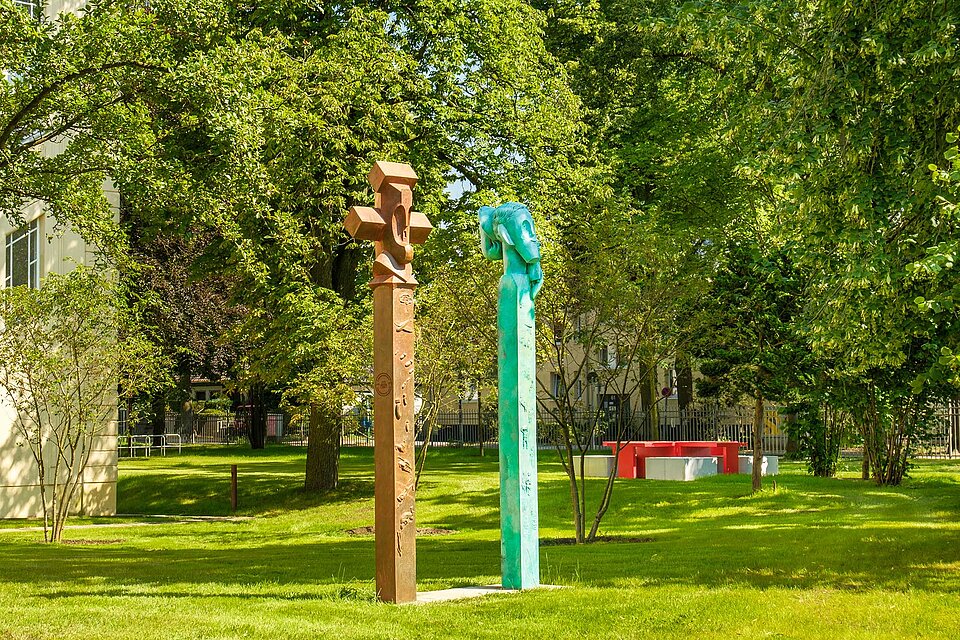 Skulpturenpaar und Friedenstisch zwischen Bäumen