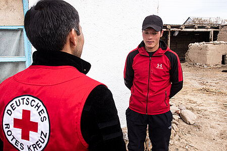 Ein junger Mensch im Gespräch mit einem Mitarbeiter vom Deutschen Roten Kreuz in Kirgistan.