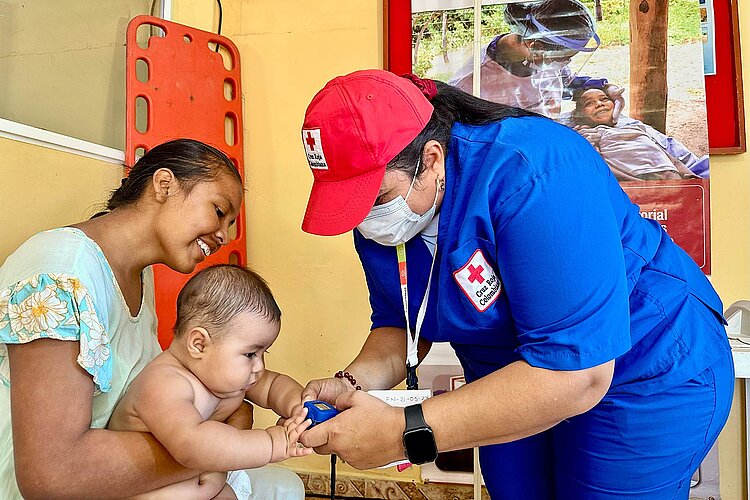 Rotkreuzlerin untersucht Baby auf Schoß der Mutter