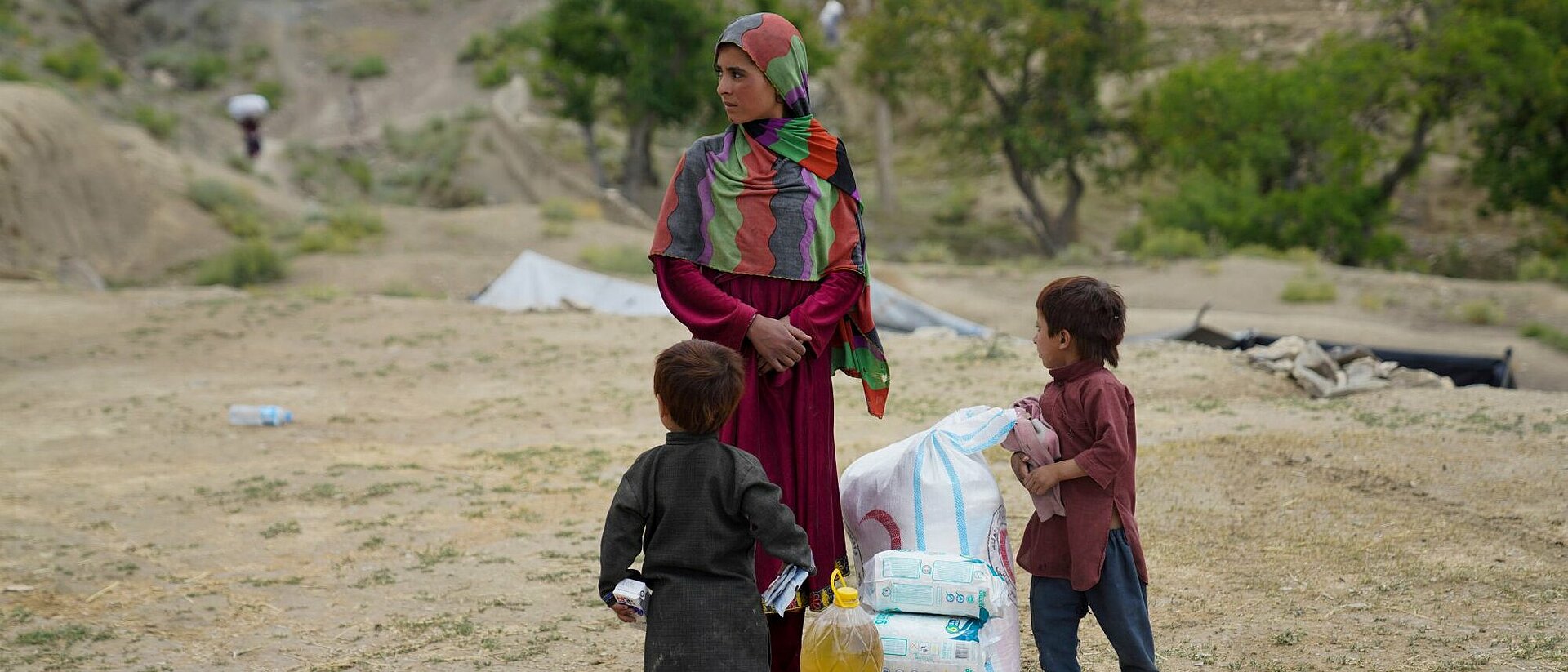 Frau mit zwei Kindern und Hilfsgütern in Afghanistan 