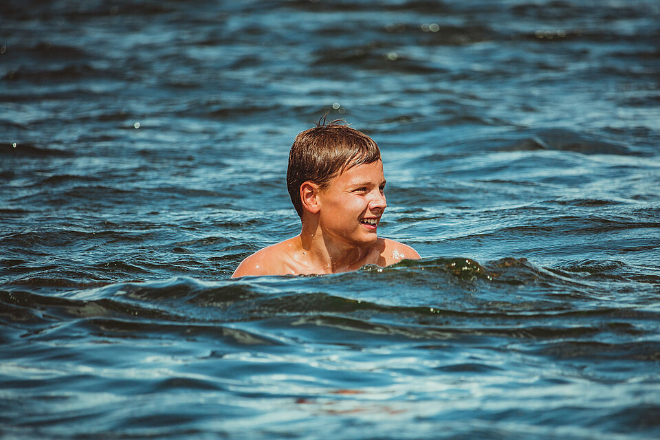 Junge schwimmt in einem See.