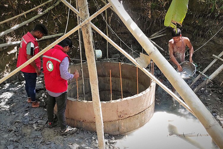 Drei Helfer an Betonringen bei Brunnenbau