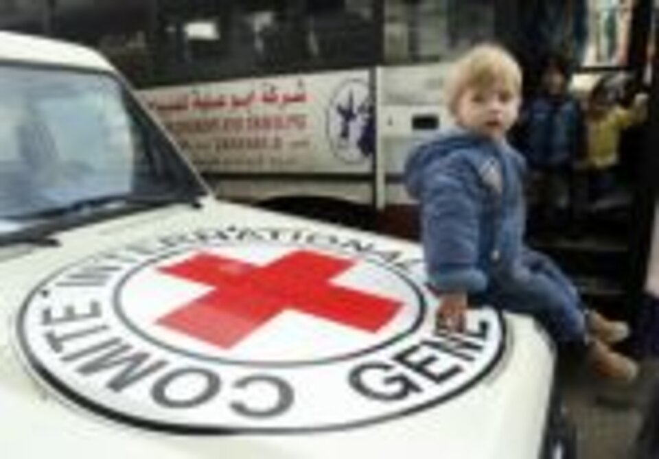 Foto: Ein kleiner blonder palästinensischer Junge sitzt auf der Motorhaube eines Rotkreuz-Jeeps.