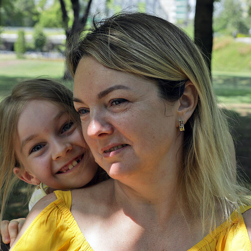 Mädchen schmiegt sich lachend an Mutter