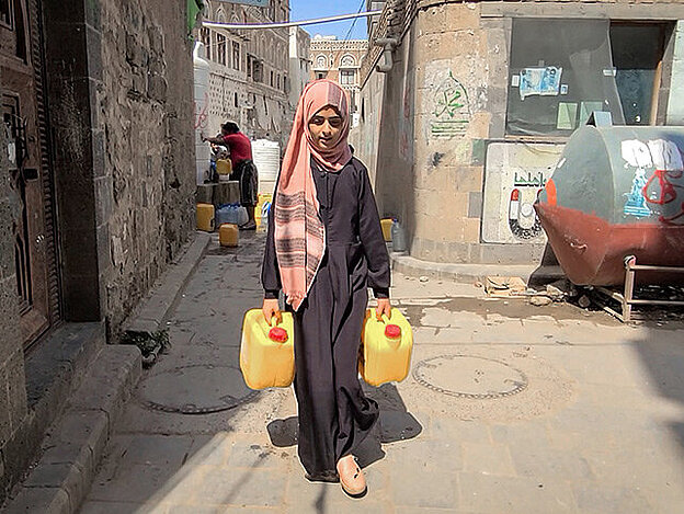 Jemenitisches Mädchen mit Wasserkanistern in Straße