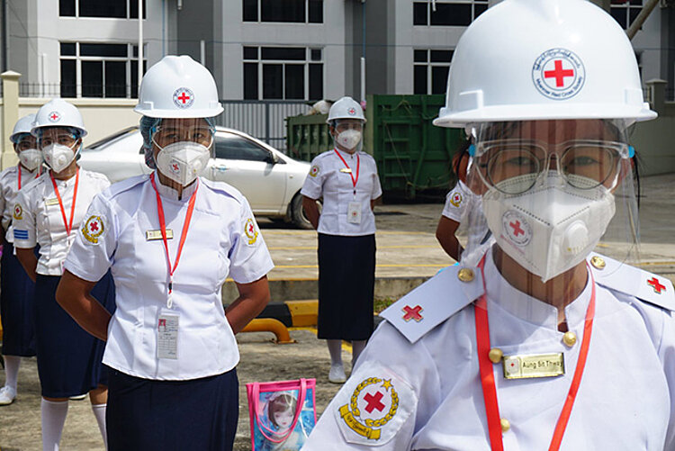 Freiwillige des Myanmarischen Roten Kreuzes in Uniform und Infektionsschutzausrüstung
