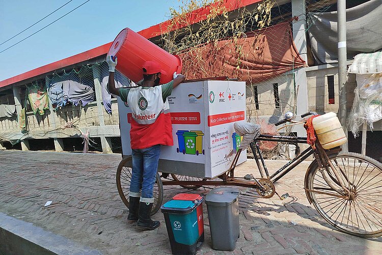 Helfer kippt Müll in Container auf Lastenfahrrad