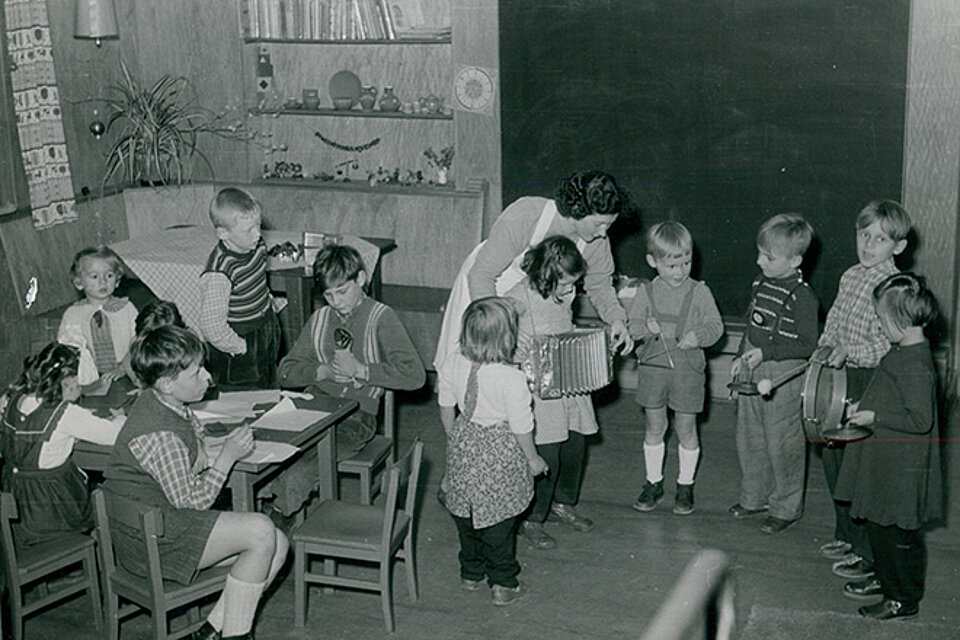 historisches Foto: Kinder und Erzieherin beim Musizieren