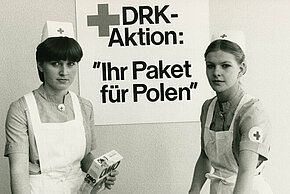 Deutsche Rotkreuzschwestern mit einem Standardpaket im Wert von fünfzig DM, das Lebensmittel und Hygieneartikel enthält (DRK)
