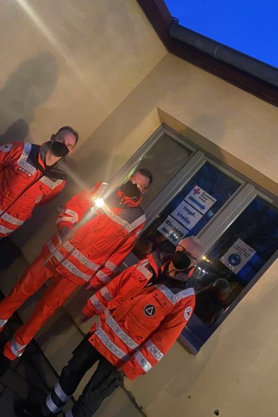 Der Bereitschaftsleiter SEE-Sanität DRK-Kreisverband Gransee e.V. Ronny Schüler, Kamerad der SEE-Sanität Patrick Herrmann und Kamerad der SEG Bt./V Dieter Schirmer mit der Fackeln vor der Impfstelle Zehdenick