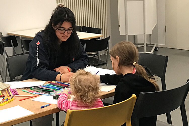 DRKlerin malt mit zwei Kindern