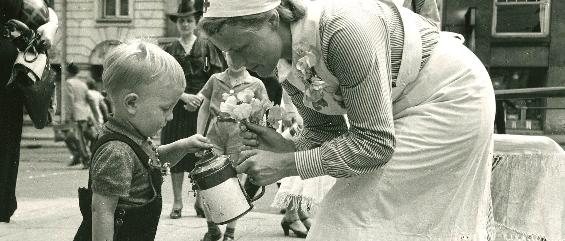 Kleiner Junge wirft Geld in Spendendose einer DRK-Helferin
