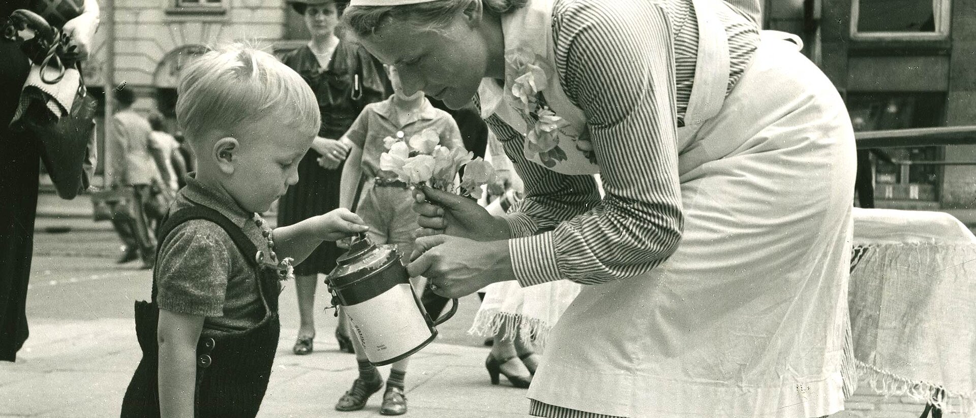 Kleiner Junge wirft Geld in Spendendose einer DRK-Helferin