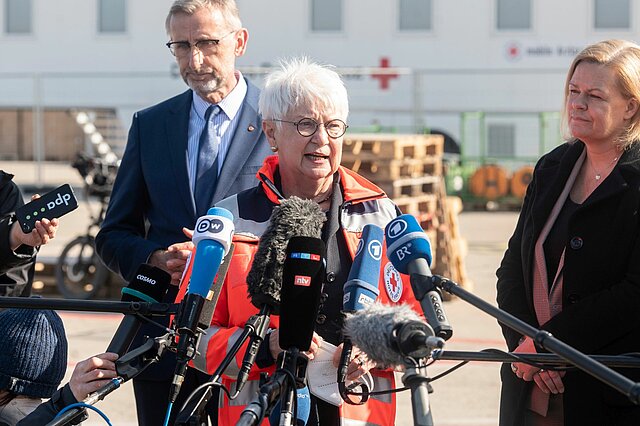 Ankunftszentrum für rund 1.000 Geflüchtete aus der Ukraine auf dem Gelände des früheren Flughafens Berlin - Tegel in Berlin - Reinickendorf. Besichtigung durch DRK-Präsidentin Gerda Hasselfeldt, Bundesinnenministerin Nancy Faeser, DRK-Generalsekretär Christian Reuter und den Präsidenten des Bundesamtes für Bevölkerungsschutz und Katastrophenhilfe Armin Schuster und Pressekonferenz. Gerda Hasselfeldt spricht zu Journalisten, hinter ihr Armin Schuster und Nancy Faeser