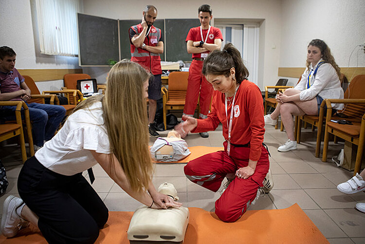 Rotkreuzlerin und junge Frau bei Erste-Hilfe-Übung