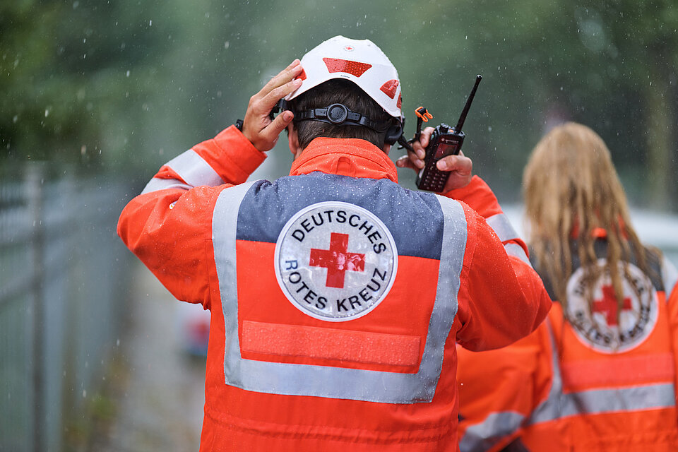 Mitarbeiter vom DRK in Einsatzjacke bei Regen. (©Willing-Holtz/DRK) 