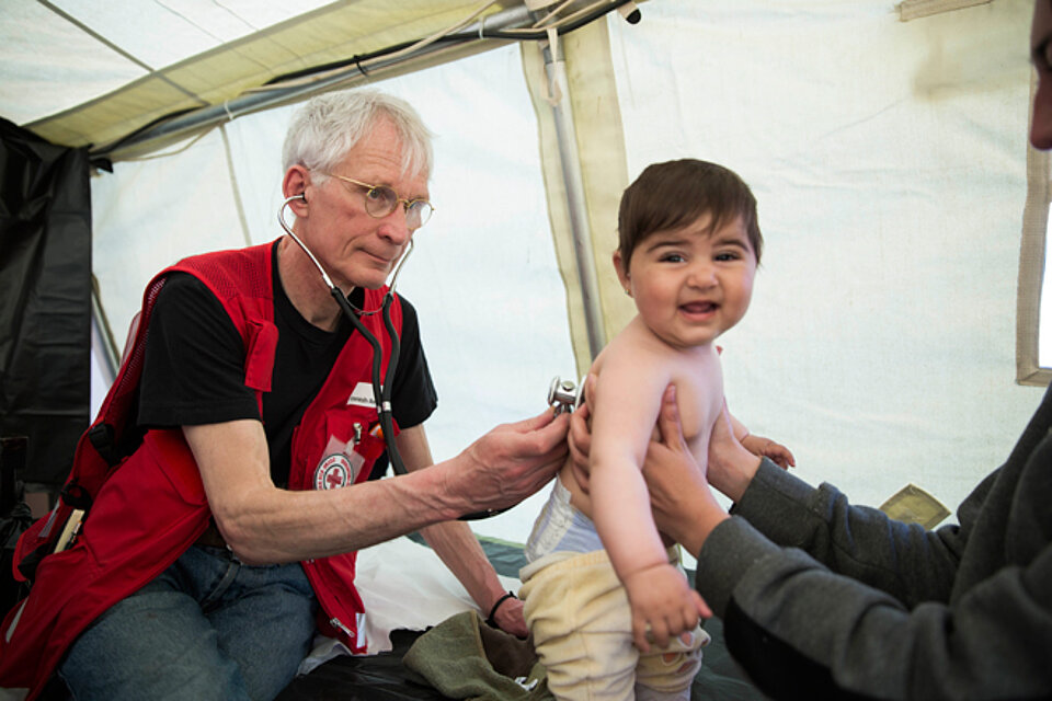 Foto: DRK-Arzt hört ein Flüchtlingskind ab.