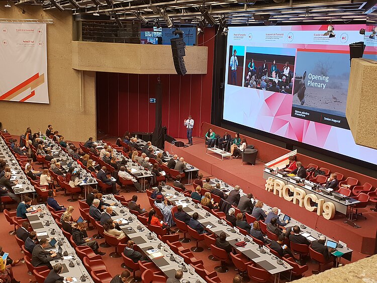 In einem großen Saal sitzen viele Delegierte in Reihen vor der Bühne