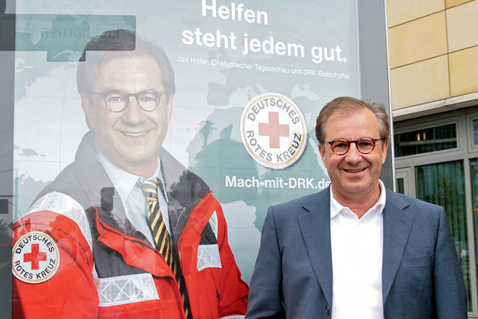 Foto: Jan Hofer vor einem DRK-Plakat mit ihm drauf