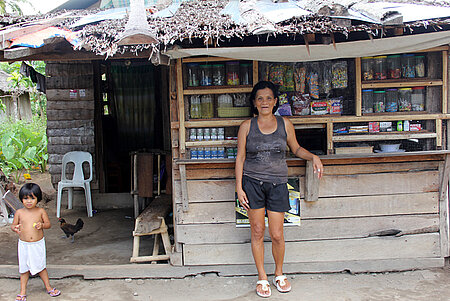 Eine Philippinin nach Wiederaufbaumaßnahmen vor ihrem Kiosk