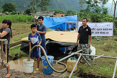 Menschen aus Vietnam vor einer Wasserpumpe