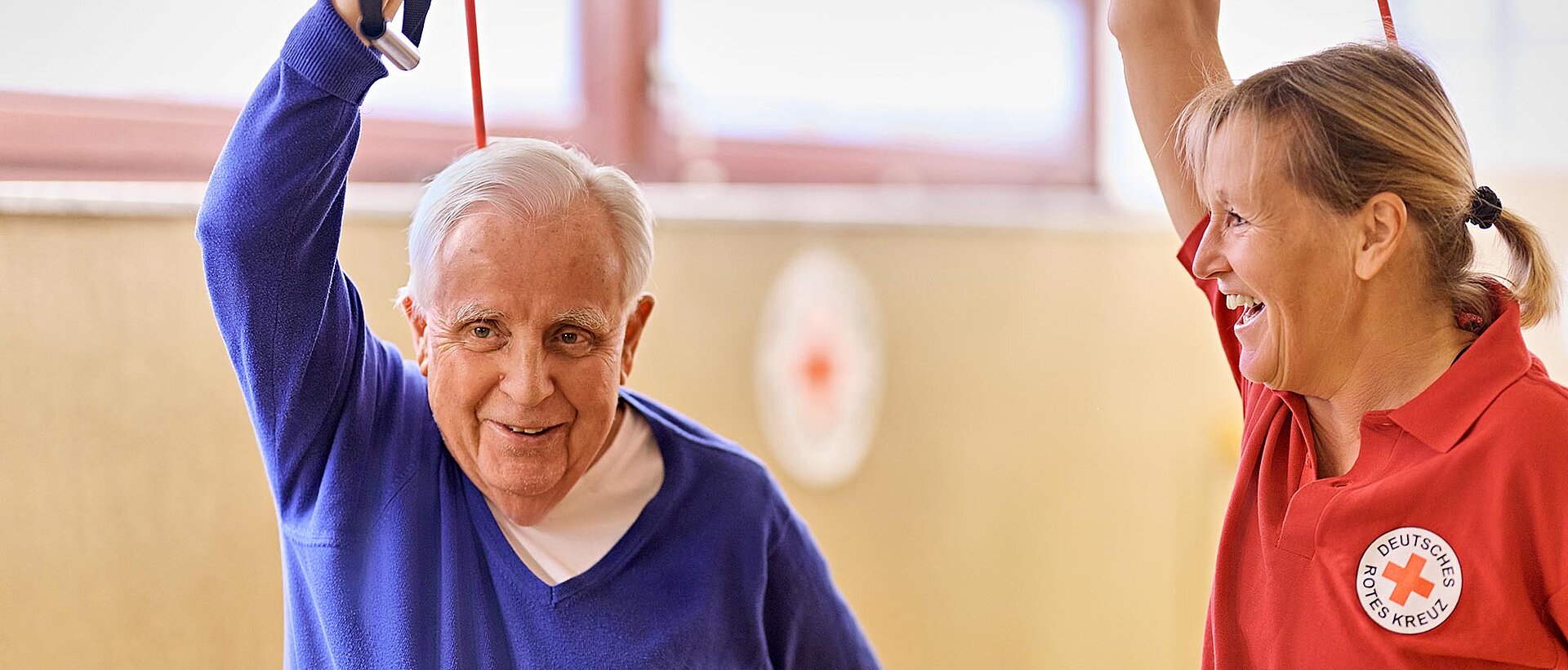 Senior und DRKlerin bei Gymnastik mit Expander