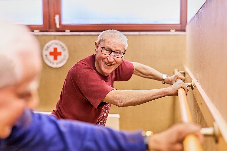 Senior an Stange beim Dehnen