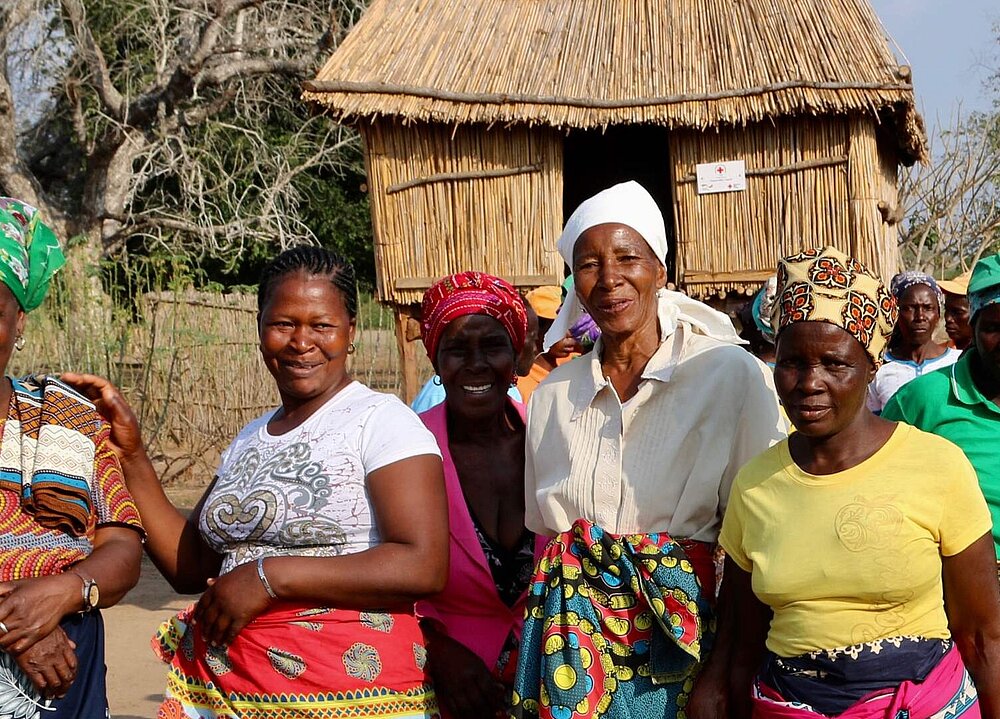 Eine Gruppe Frauen in bunter Kleidung stehen vor einem vom DRK errichteten neuen Kornspeicher.