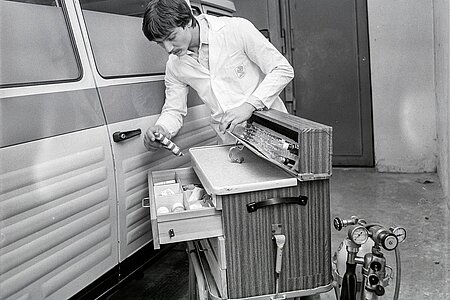 DRK-Mitarbeiter überprüft Ausrüstung vor Krankenwagen