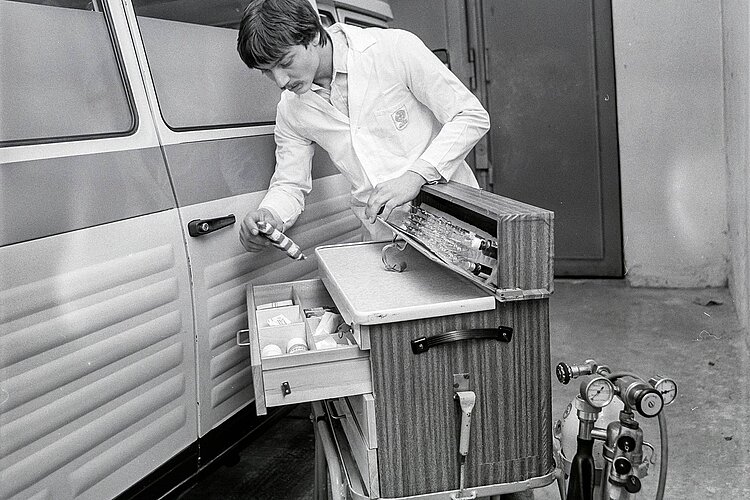 DRK-Mitarbeiter überprüft Ausrüstung vor Krankenwagen