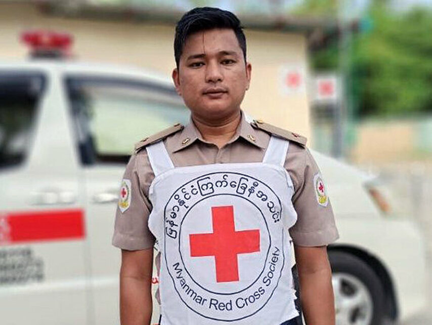 Myanmarischer Helfer mit Rotkreuzleibchen vor Einsatzwagen