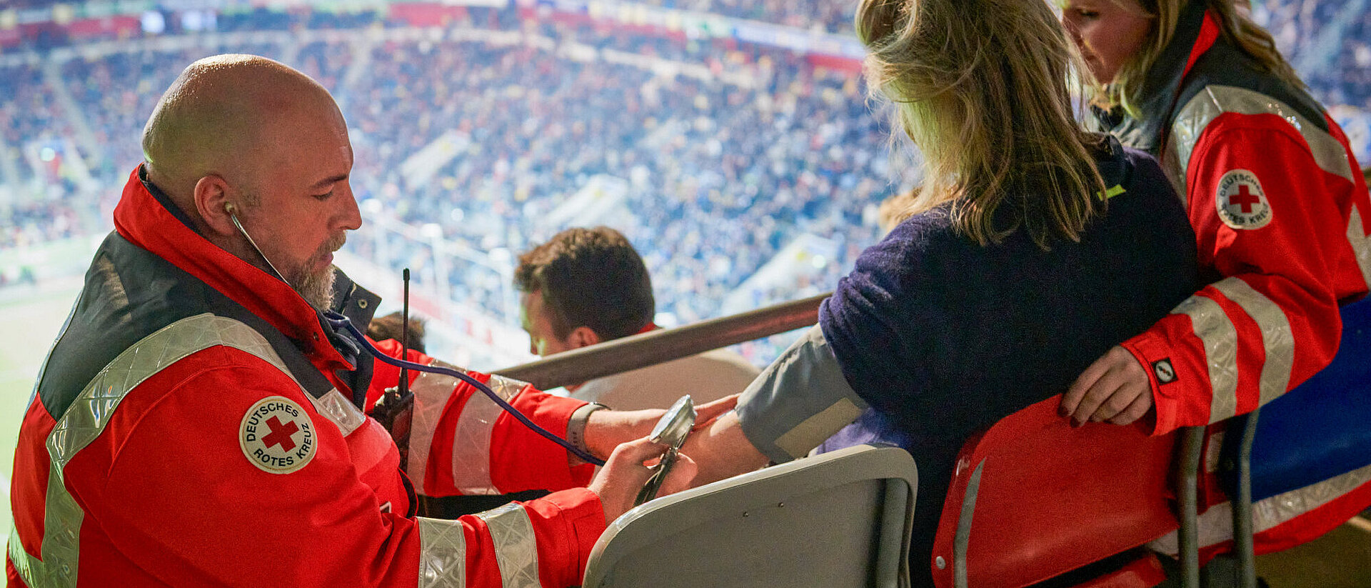 DRK-Sanitäter misst den Blutdruck bei einer Zuschauerin im Stadion