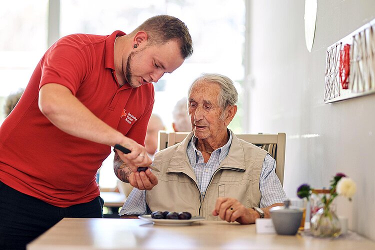 DRK-Pfleger hilft Senior beim Pflaumenentsteinen