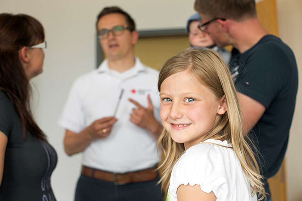 Mädchen mit Elterngespräch im Hintergrund