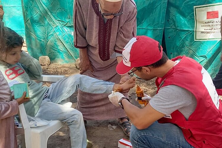 Helfer des Marokkanischen Roten Halbmonds leistet Erste Hilfe für Betroffene.
