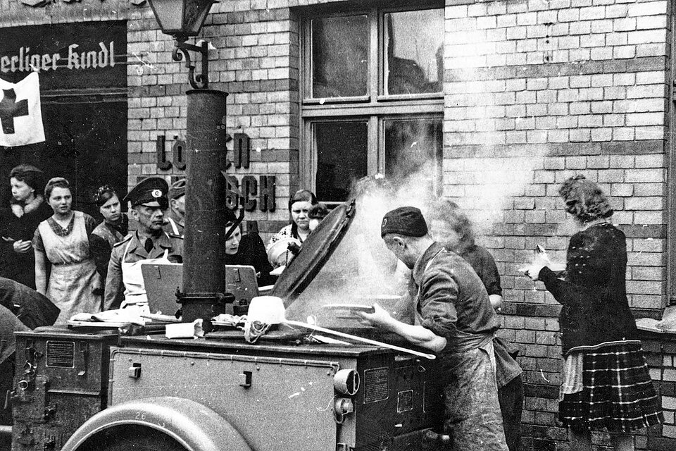 Menschen stehen um Feldküche