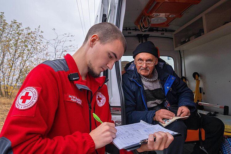 Winterhilfe in der Ukraine Rokreuzler schreibend vor Mann im Fahrzeug